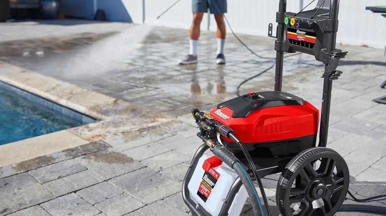 Man pressure washing a pool deck with a Bauer machine