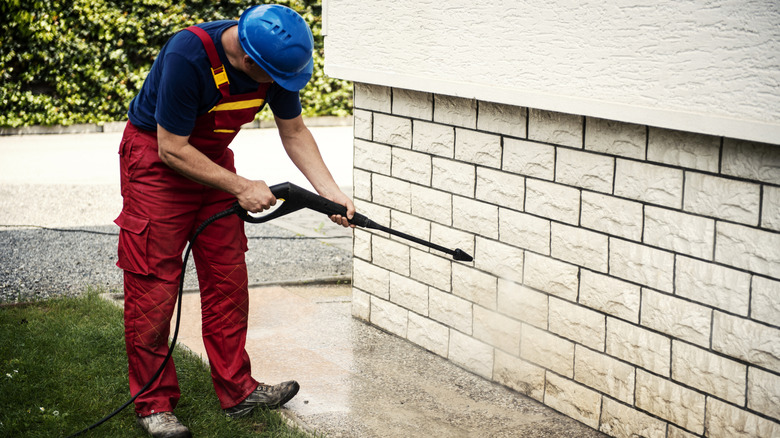 Person pressure washing brick on a house