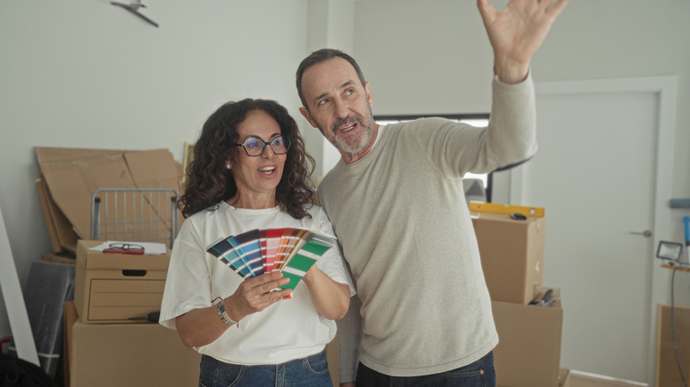 Couple holding a handful of paint chips and looking at room to paint