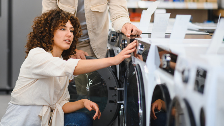A couple looking at front load washers in a store