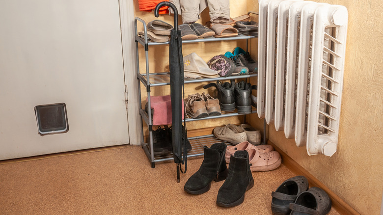 Cluttered shoes by entryway on shelf and on the floor