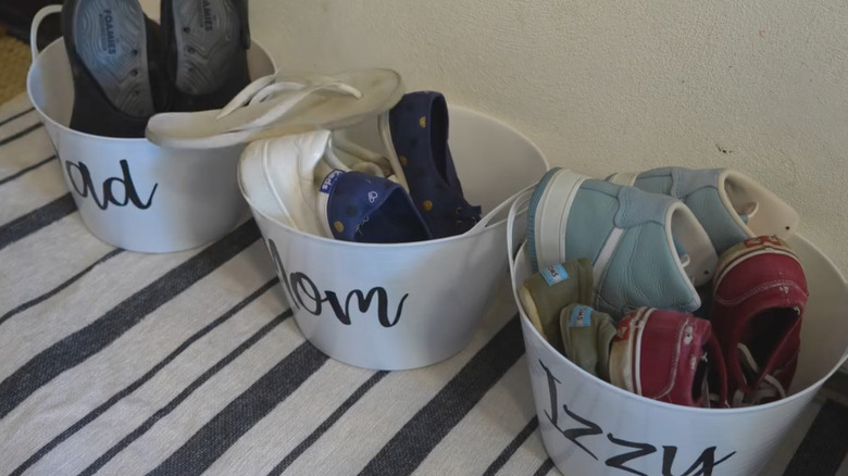 Photo showing white buckets holding shoes with name labels on them