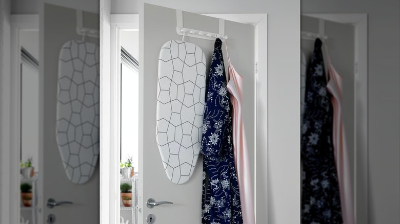 ENUDDEN on the back of a door holding an ironing board and two articles of clothing