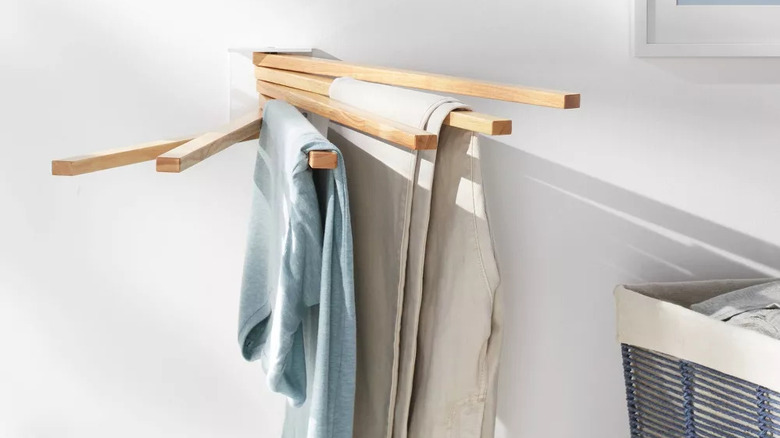 woman hanging clothes on a wall-mounted clothing rack