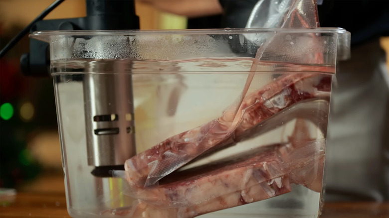 Vacuum-sealed meat being cooked in a container using a sous vide cooking machine