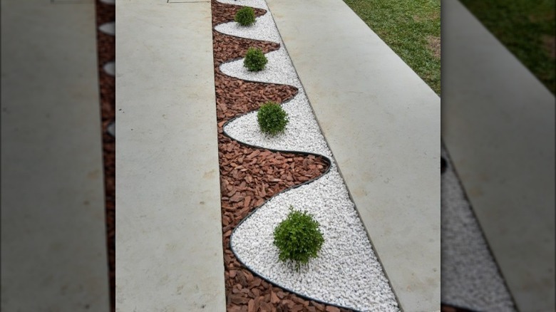 Mix of wood chips and pea gravel used to make serpentine-shaped edging for concrete driveway