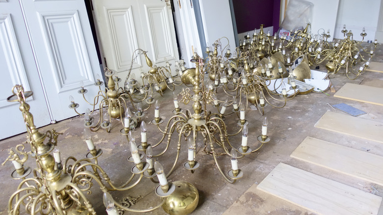 Chandeliers salvaged from a hotel sitting on the floor with salvaged doors behind.