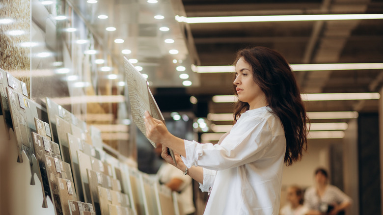 A woman looks at bathroom wall and floor finishes in a showroom.