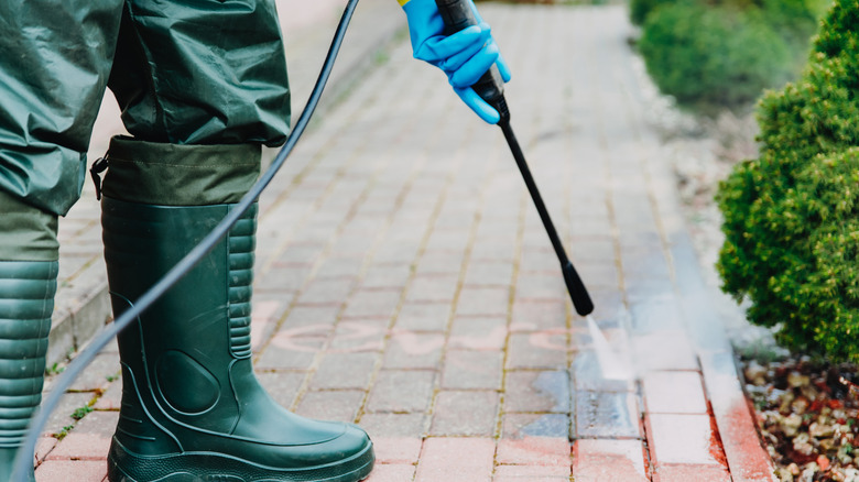 person pressure washing pavers