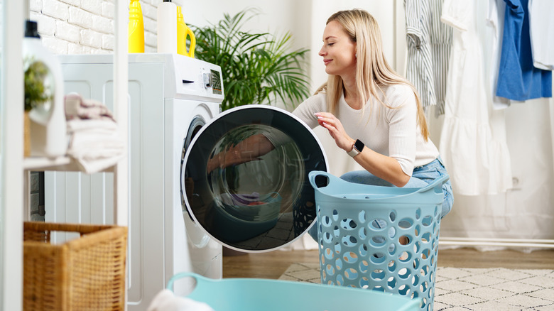 A woman removes clothing from a washing machine.