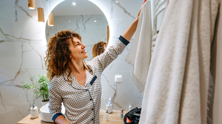 Woman hanging towel in bathroom