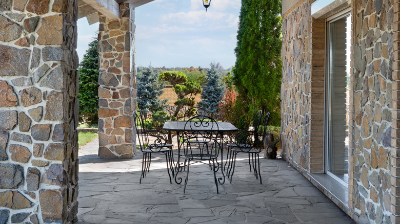 A covered stone porch with a dining set