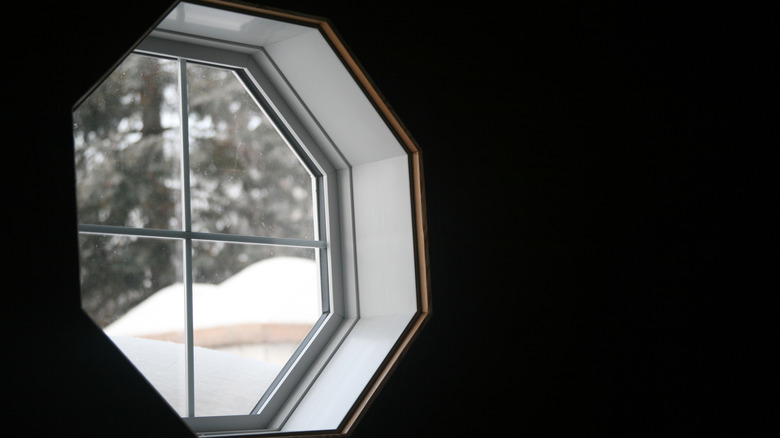 An octagonal window with snow outside.