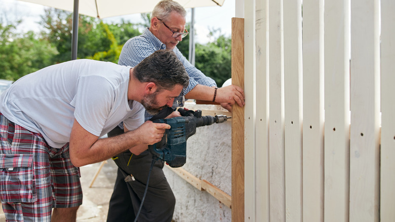 Two people installing a new fence