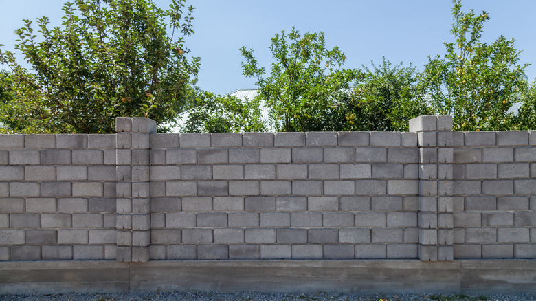 A cinder block fence with trees behind it