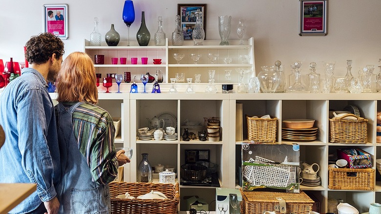 Back view of two people browsing antique or vintage shop for glassware