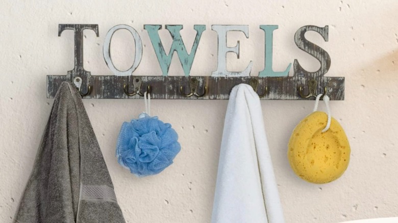 The MyGift wall mounted towel rack on Amazon with towels and shower sponges hanging on hooks.