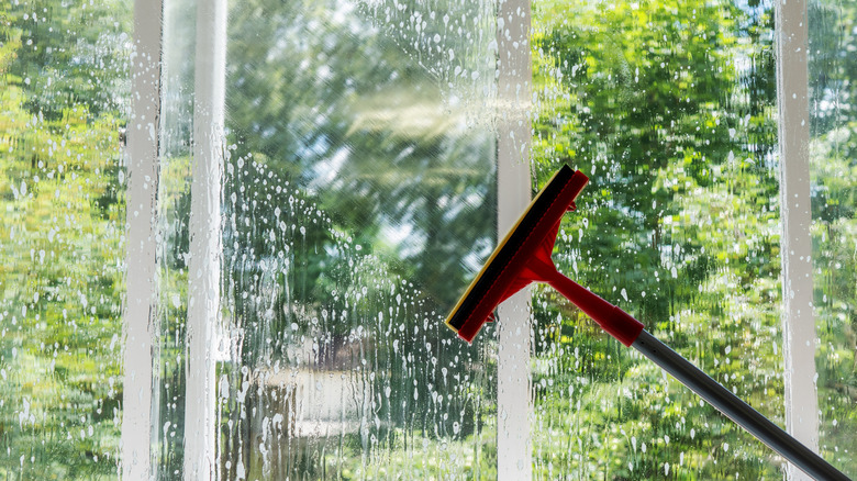 A squeegee is used to clean a large glass window