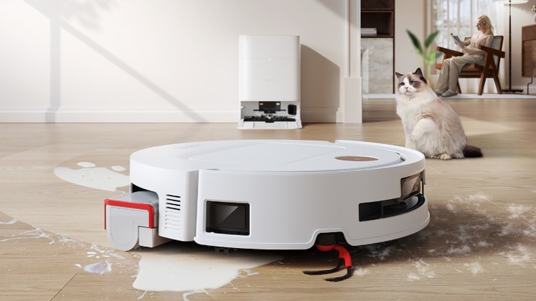 YEEDI M14 Plus vacuum and mop model in white cleaning up mess with cat in the background