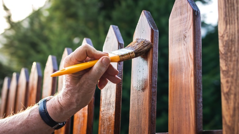 Man applying wood finish outdoors 