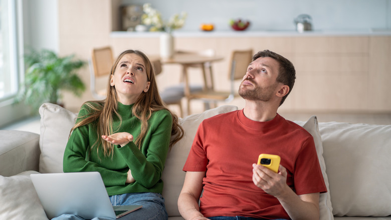 An annoyed couple looks up at the ceiling