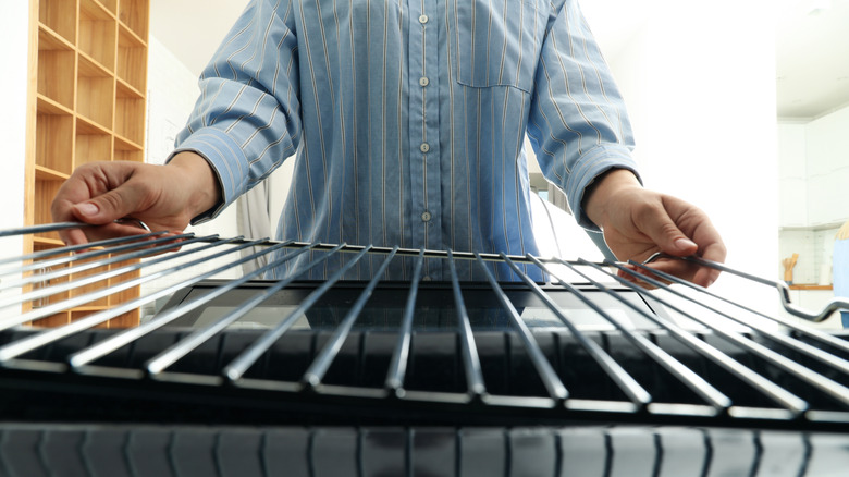 close up of a man holding an oven rack