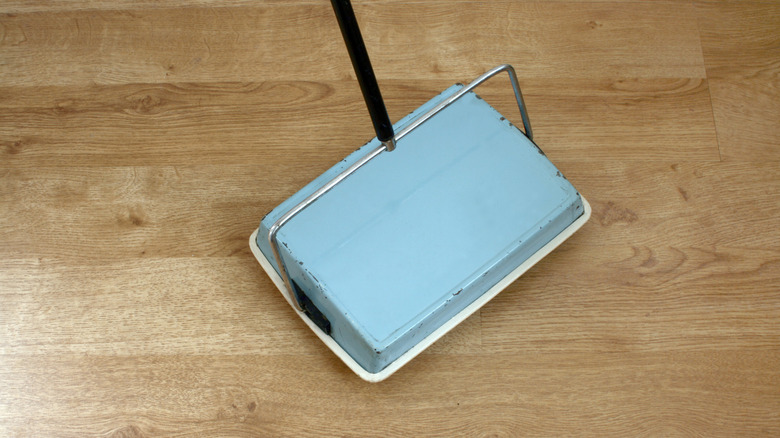 A vintage carpet sweeper on a wooden floor