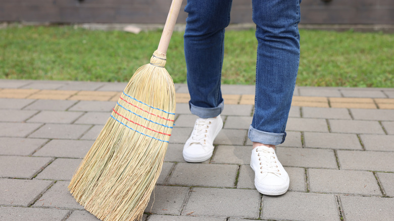 Close-up of a person using a corn broom outdoors