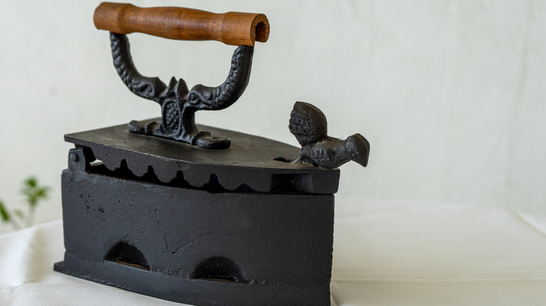 Ornate cast-iron clothes iron on a white sheet