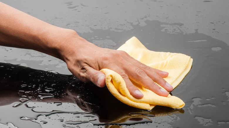 Close-up of a hand cleaning the surface of a car with a chamois