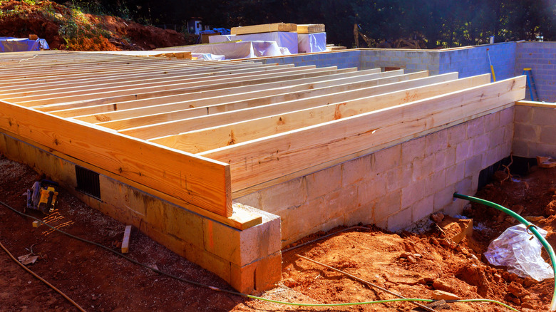 Workers are constructing new building with wooden beams on cinder block foundation