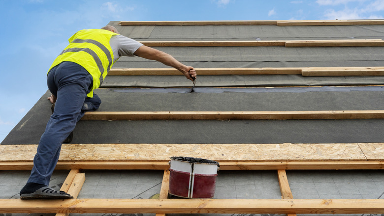 Man installing tar paper on roof