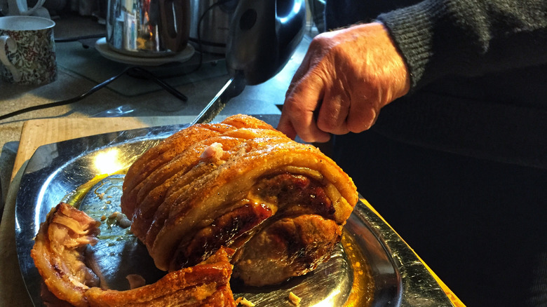 hands using electric knife to cut roast