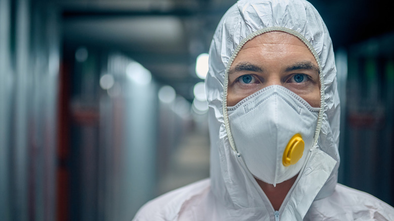 A man wearing protective gear to remove asbestos tiles