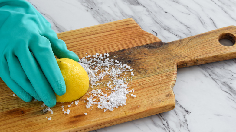 person pressing a half lemon into salt with a blue glove