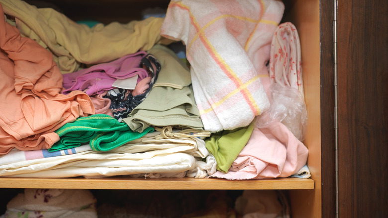 A messy linen closet with towels