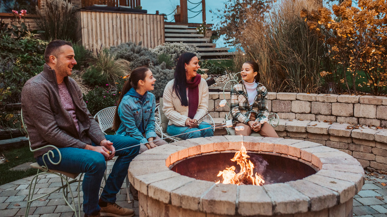 A family sitting in front of a fire pit and roasting marshmallows
