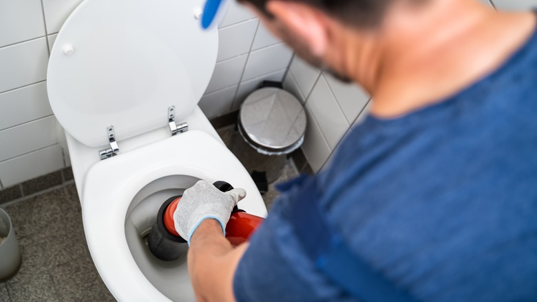 Man vacuuming water from toilet