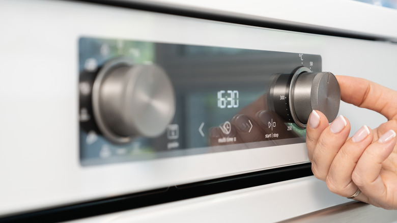 A hand turning a knob on an oven