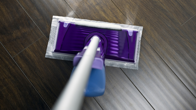 Swiffer Wet Jet mop spaying water on a wood vinyl floor.