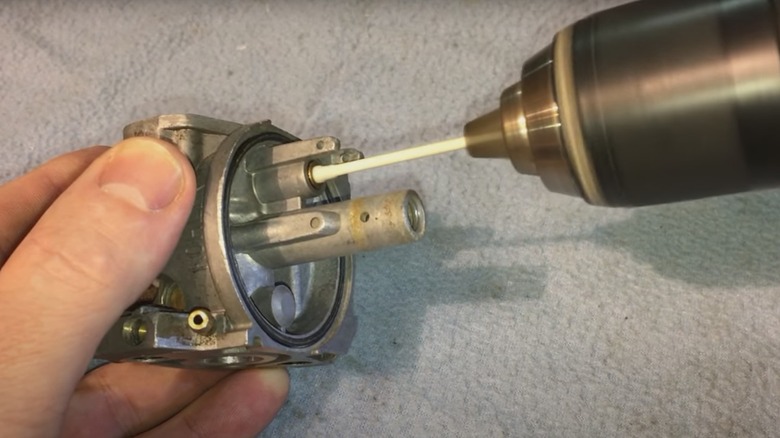 Power drill with a cotton swab being used to clean a carburetor seat