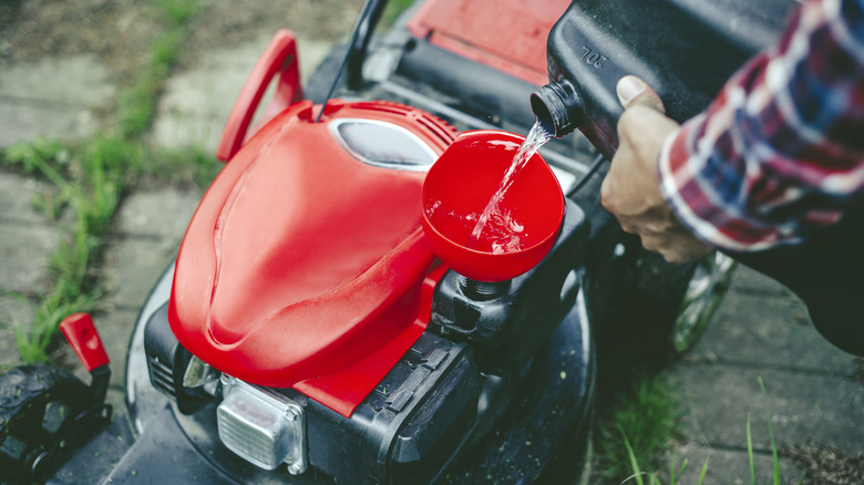 a person refilling a lawn mower with gasoline