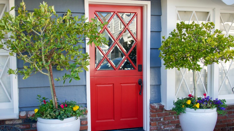 A cottage with a bright red Dutch door and small trees