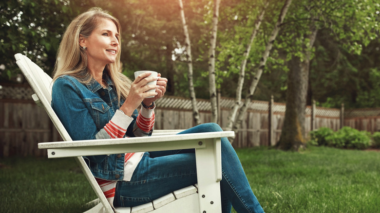 Woman relaxes in her backyard, gazing at her new lush privacy wall