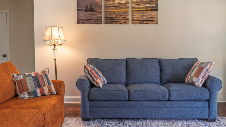 A blue and an orange couch in a living room with stylish pillows at each end