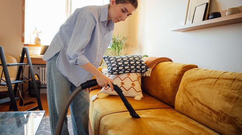 A person cleaning their couch with a vacuum cleaner