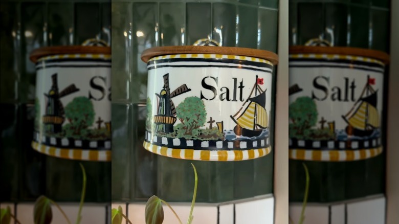 A thrifted salt cellar with newly painted exterior attached to the tiled wall of a kitchen.