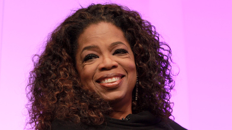 Oprah Winfrey smiling against a pink background