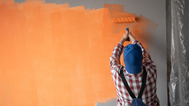 person painting a wall orange