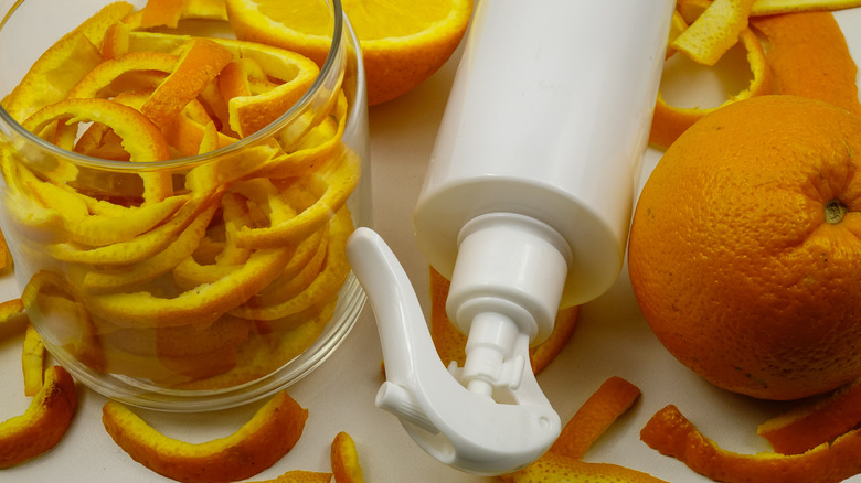 orange peels soaking in jar next to a spray bottle and a whole orange